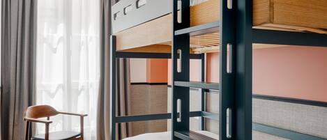 Habitación con literas, un escritorio, una silla, un taburete redondo y una lámpara colgante.