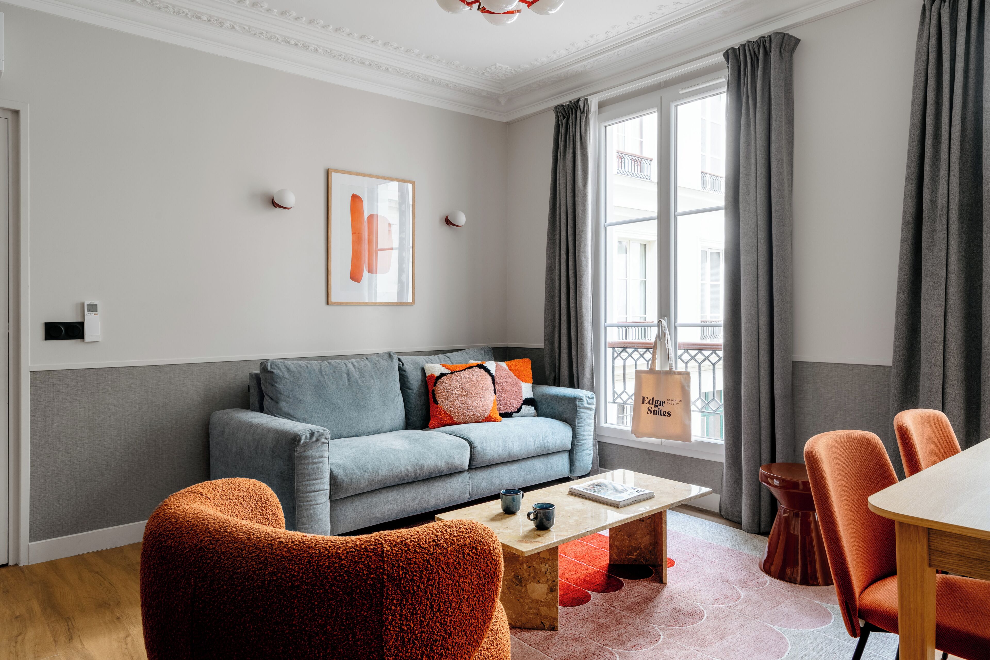 A modern living room with a grey sofa, orange armchair, and a coffee table.