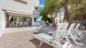A modern building with a patio area featuring outdoor seating and a view of the surrounding landscape. - Holiday Home “Aloe” with Garden, Terraces & Wi-Fi (Son Serra de Marina)