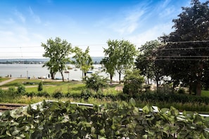 A park with a river, trees, and a distant view of a city. - Central Apartment "Reichenaublick" on Lake Constance with Lake and Mountain Views (Allensbach)