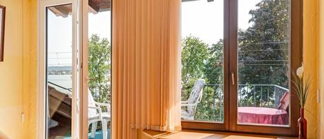 Une pièce dotée d’une porte-fenêtre coulissante, d’une table en bois, d’un radiateur et donnant sur un balcon extérieur.