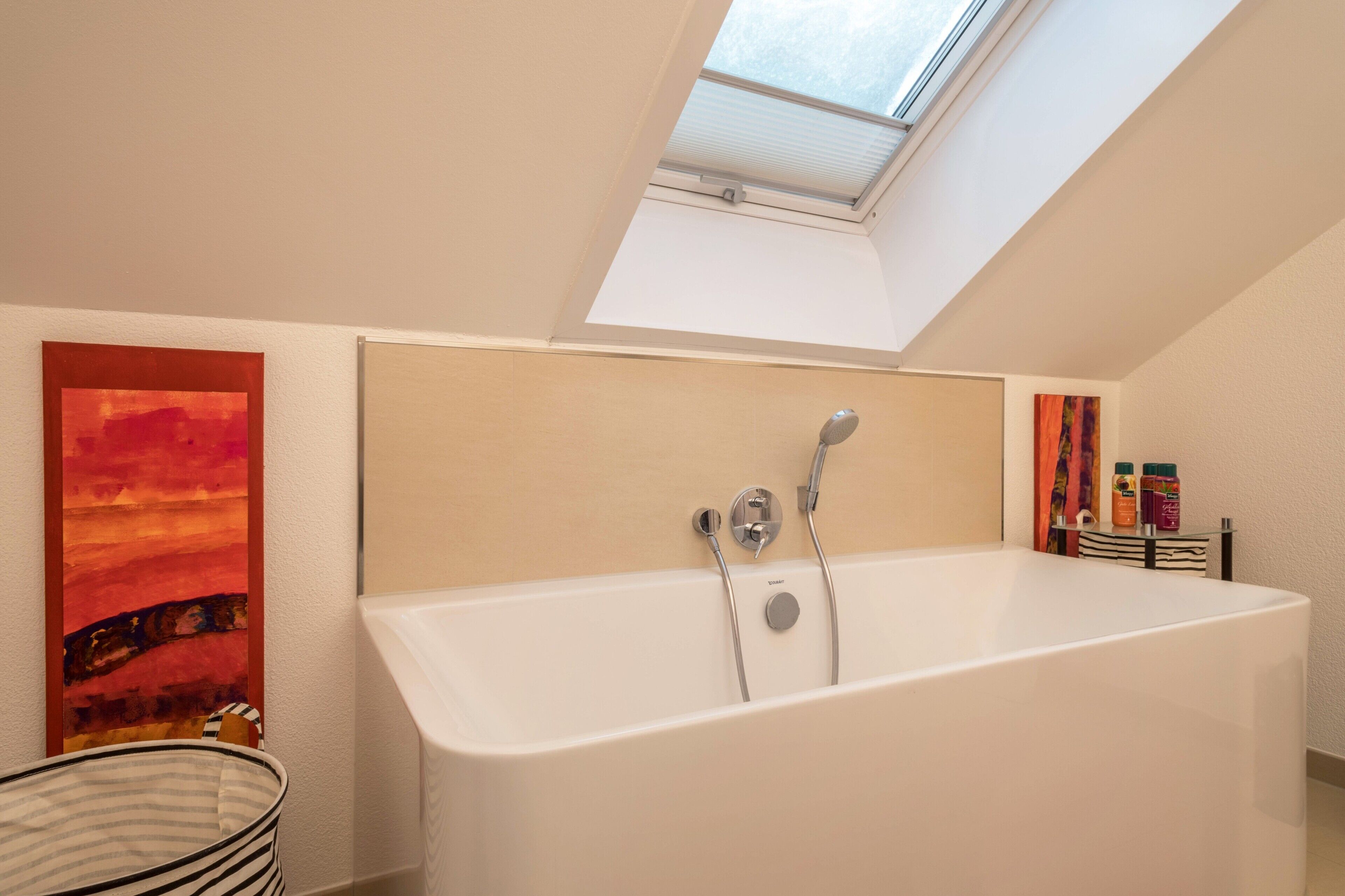 A modern bathroom with a skylight, a bathtub, and a shower area.