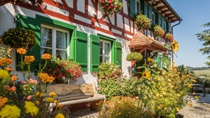 A traditional half-timbered house with a stone pathway, wooden bench, and flower boxes on the windowsills. - Holiday Apartment "Risthof 1" with Wi-Fi, Shared Garden, Sauna & Playground (Owingen)