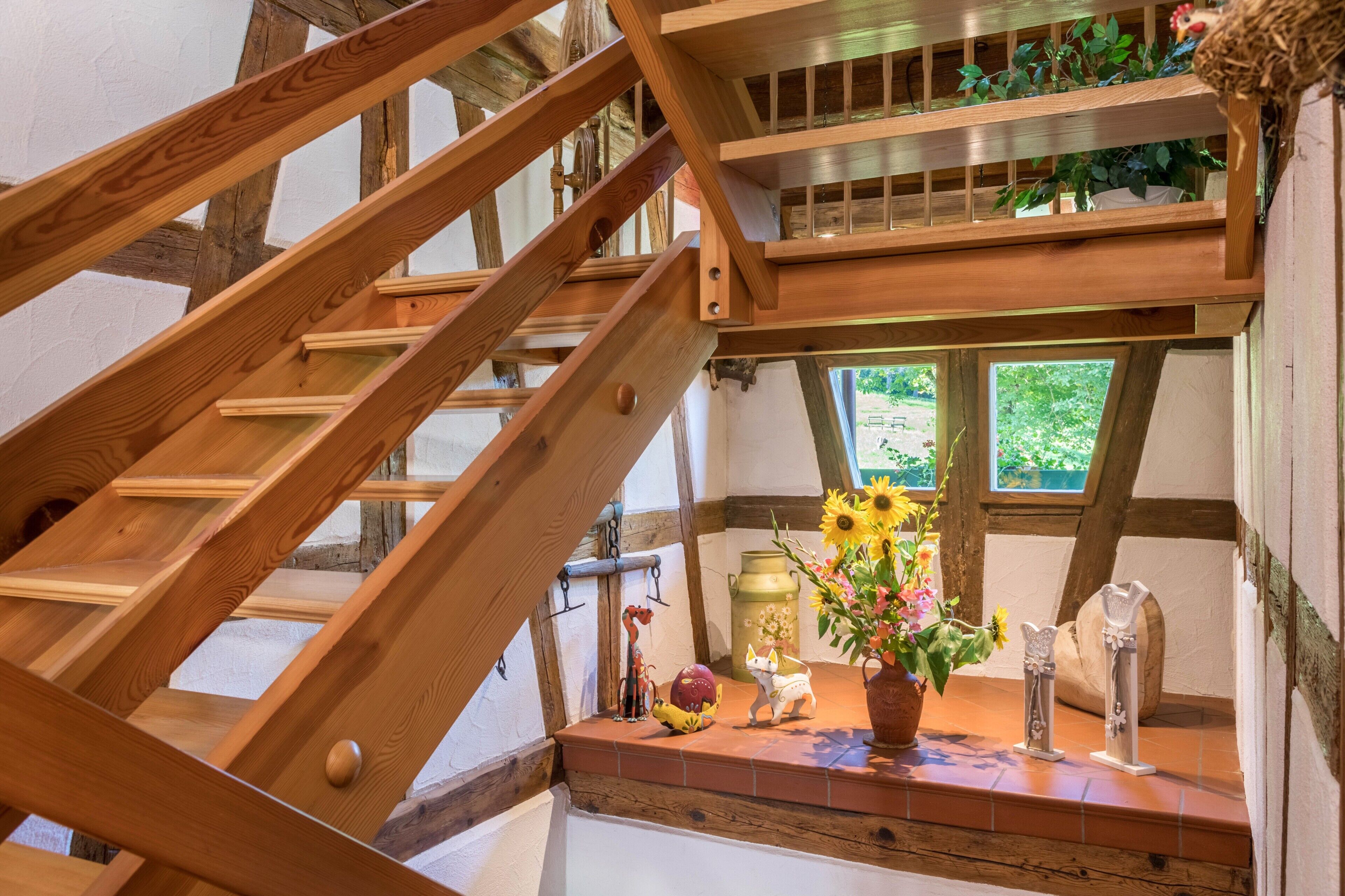 Eine Holztreppe mit Blick auf ein Fenster und einem Regal mit Dekoration.