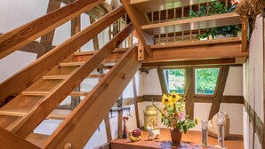 A wooden staircase with a view of a window and a shelf with decorative items. - Holiday Apartment "Risthof 1" with Wi-Fi, Shared Garden, Sauna & Playground (Owingen)