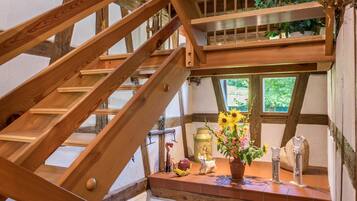 Eine Holztreppe mit Blick auf ein Fenster und einem Regal mit Dekoration.