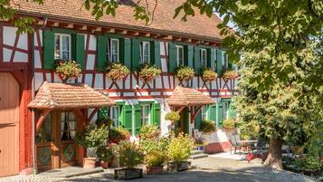 Ein traditionelles Fachwerkhäuschen mit mehreren Fenstern, einem Kopfsteinpflasterhof und Topfpflanzen.