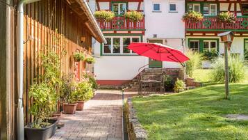 Ein Innenhof mit rotem Sonnenschirm, Blumentöpfen und einem Gebäude mit Balkon.
