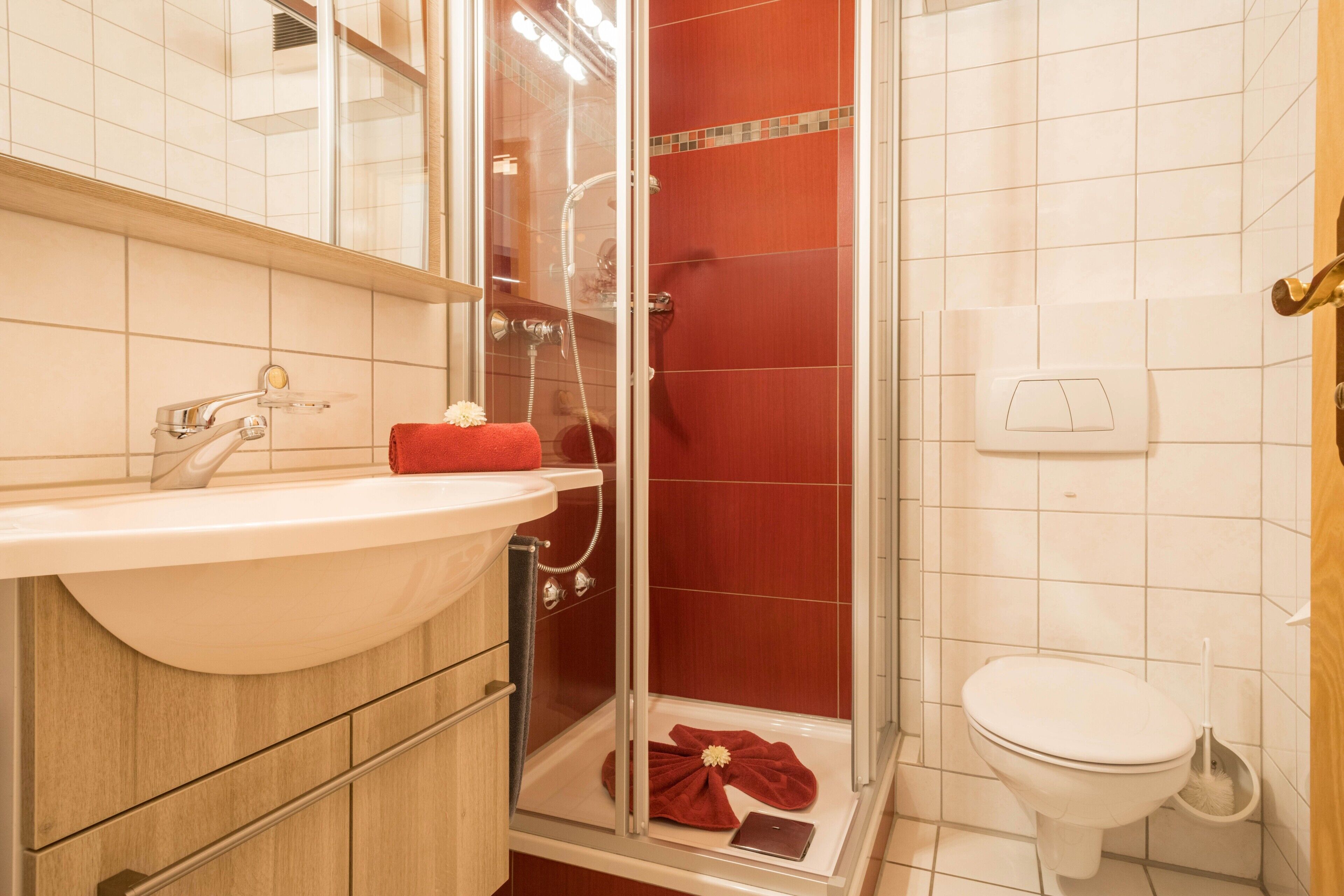 A bathroom with a white sink, a glass-enclosed shower, and a white toilet.