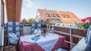 A balcony with two chairs, a table with a tablecloth, and a book. - Holiday Apartment ‘Haus Desor’ with Lake View, Wi-Fi, Balcony (Kressbronn)