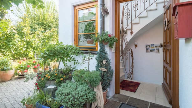 A house entrance with a wooden door, a staircase, and potted plants. - Holiday Apartment ‘Haus Desor’ with Lake View, Wi-Fi, Balcony (Kressbronn)