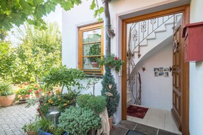 Une entrée de maison avec une porte en bois, un escalier et des plantes en pot.