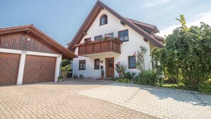 A two-story house with a wooden balcony, a garage, and a paved driveway. - Holiday Apartment ‘Haus Desor’ with Lake View, Wi-Fi, Balcony (Kressbronn)