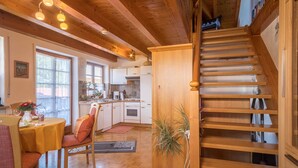 A wooden interior with a staircase, a dining area with a table and chairs, and a kitchen area. - Holiday Apartment ‘Haus Desor’ with Lake View, Wi-Fi, Balcony (Kressbronn)
