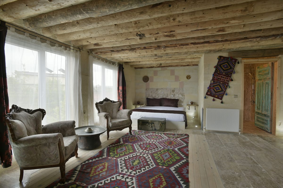A room with a bed, two armchairs, a coffee table, and a patterned rug.