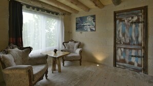 Um quarto com teto de madeira, uma janela grande com cortinas, um quadro na parede e uma porta com design rústico.
