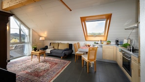 Ein gemütliches Loft-Zimmer mit Essbereich, einer Couch und einer Küche mit großem Fenster.