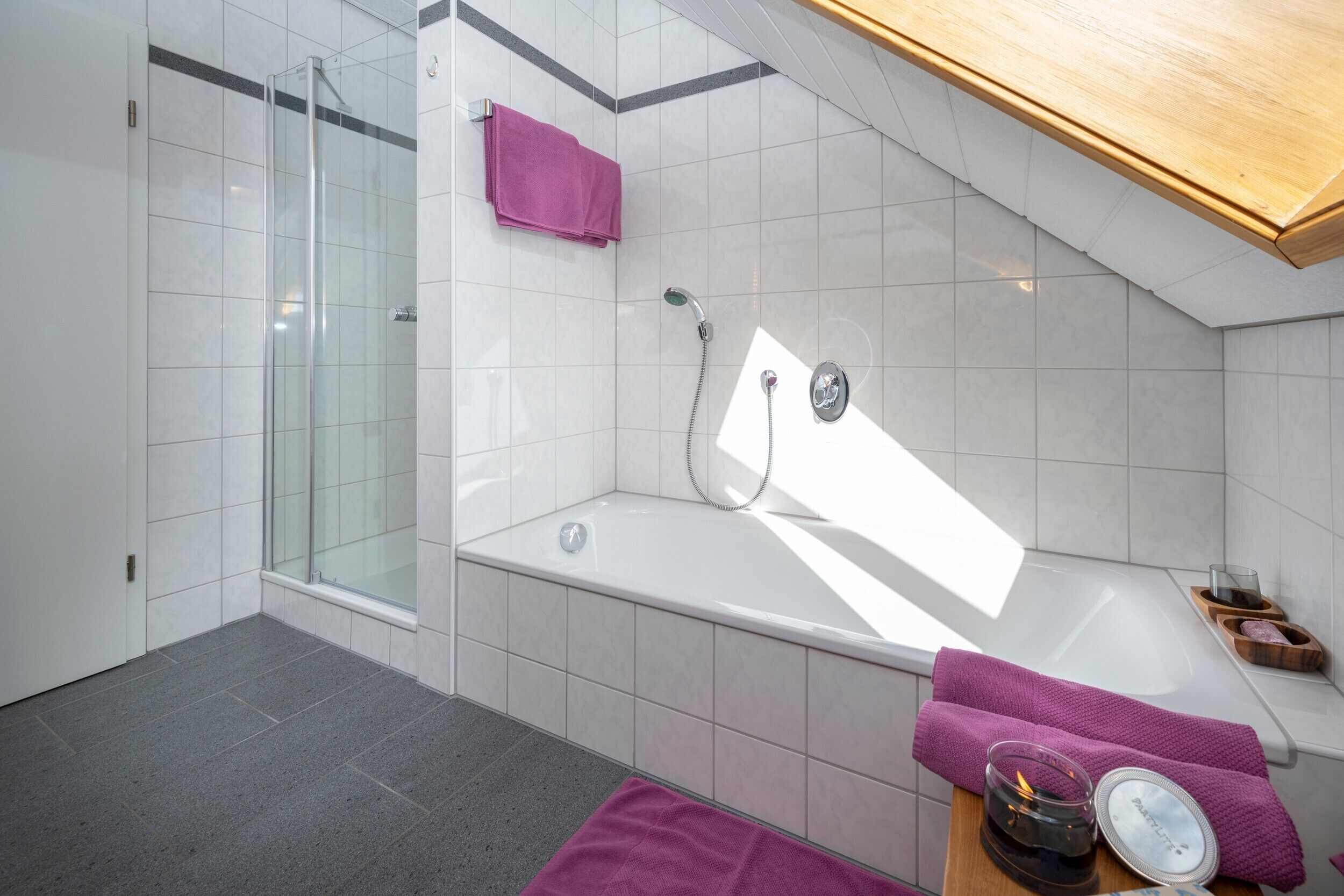 Un bany modern amb una cabina de dutxa de vidre, una banyera i un moble de tocador de fusta amb un assecador de tovalloles.