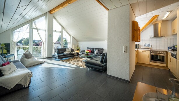 Un interior moderno con sala de estar, cocina y ventanas amplias.