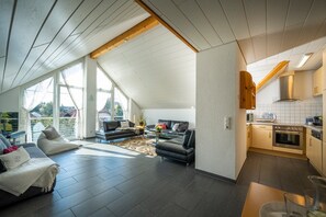 Un interior moderno con sala de estar, cocina y ventanas amplias.