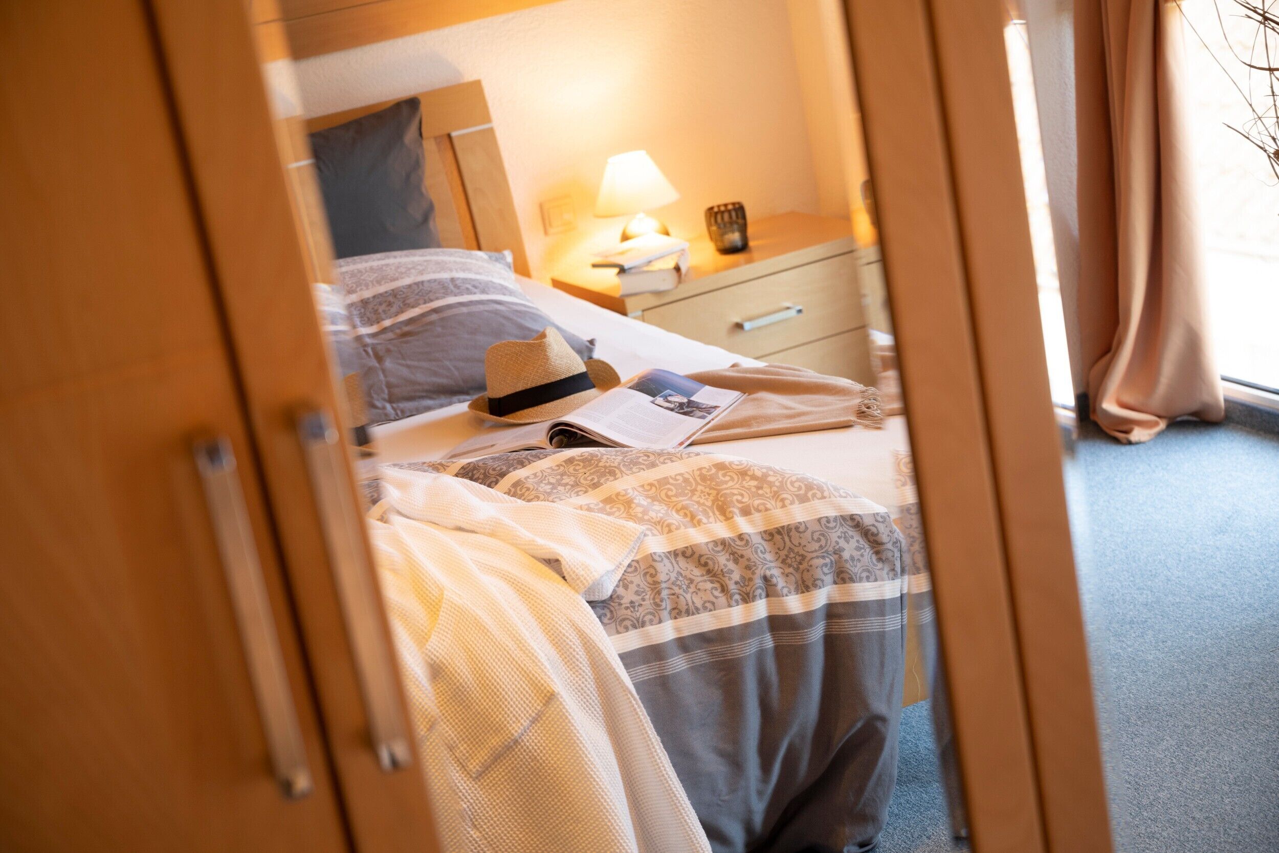 Ein Hotelzimmer mit einem Bett, einem Nachttisch, einer Lampe und einem Fenster mit Vorhängen.