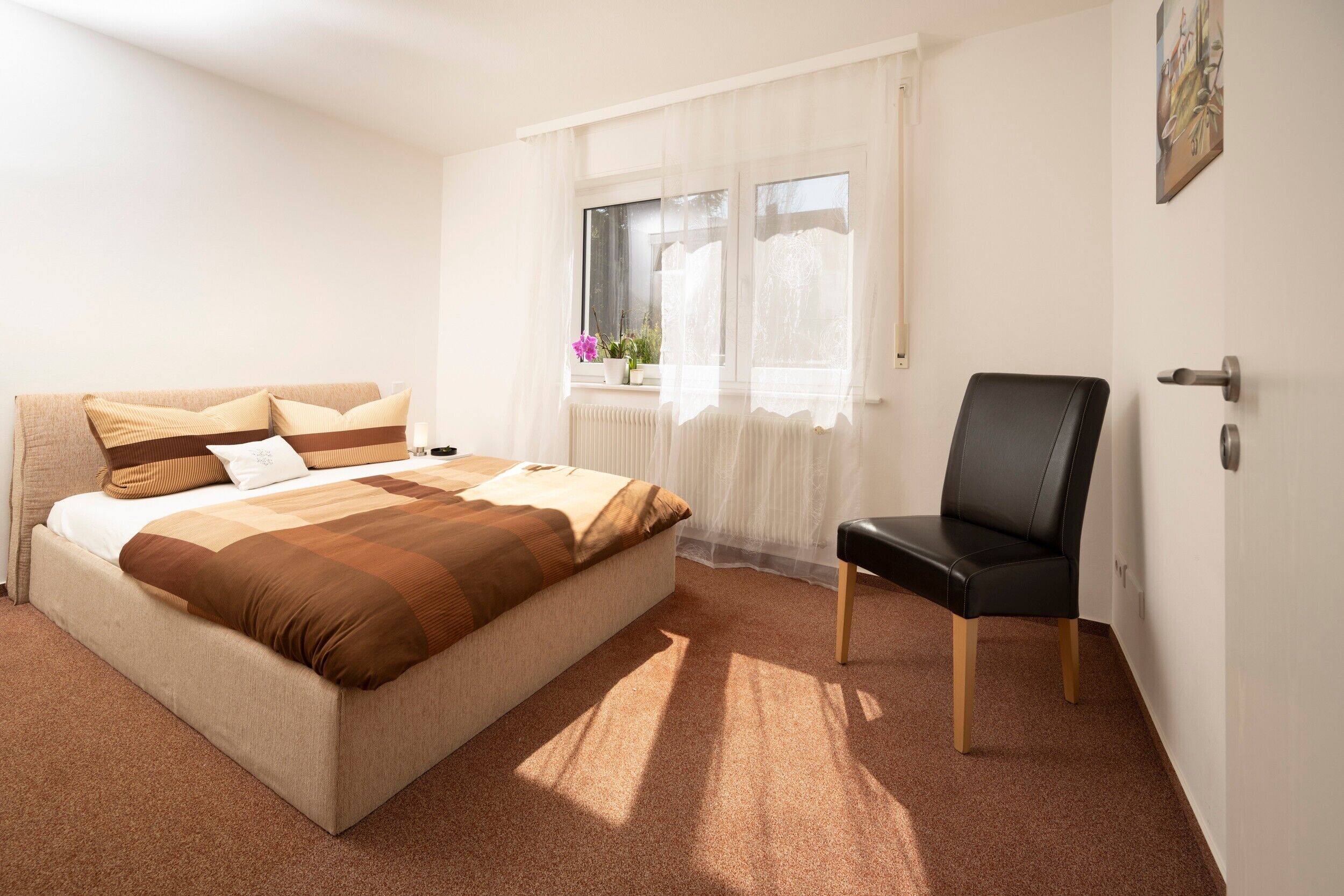 Une chambre à coucher avec un lit, une chaise, une fenêtre avec des rideaux et un radiateur.