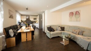 Uma sala moderna com um sofá, uma mesa de centro de vidro e uma área de jantar com uma mesa de madeira e cadeiras.