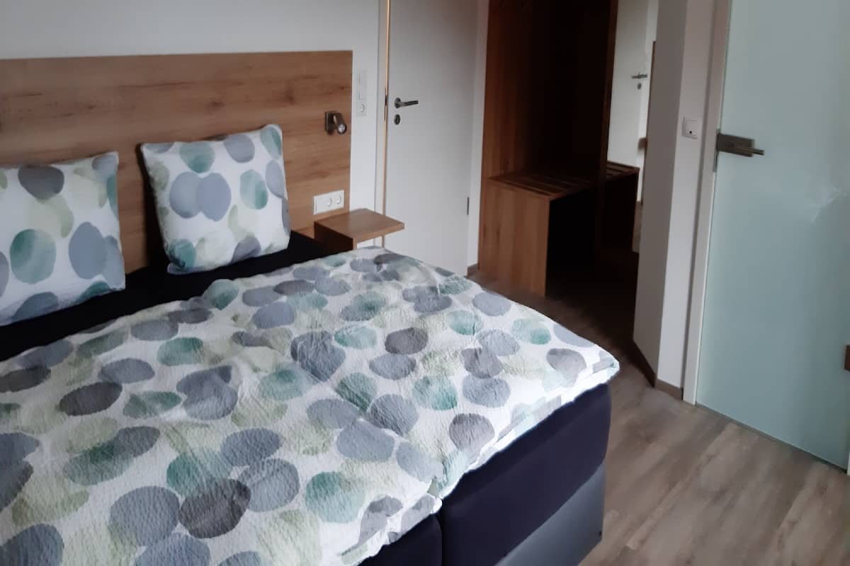 Un dormitorio con cama, cabecera de madera, mesita de noche y armario.