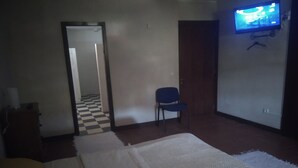 Una habitación con una cama, una silla, un televisor y un suelo a cuadros.