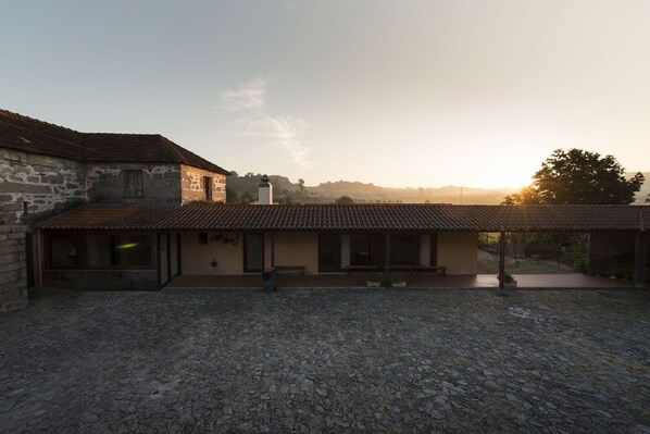 A rustic stone building with a tiled roof and a covered patio area.