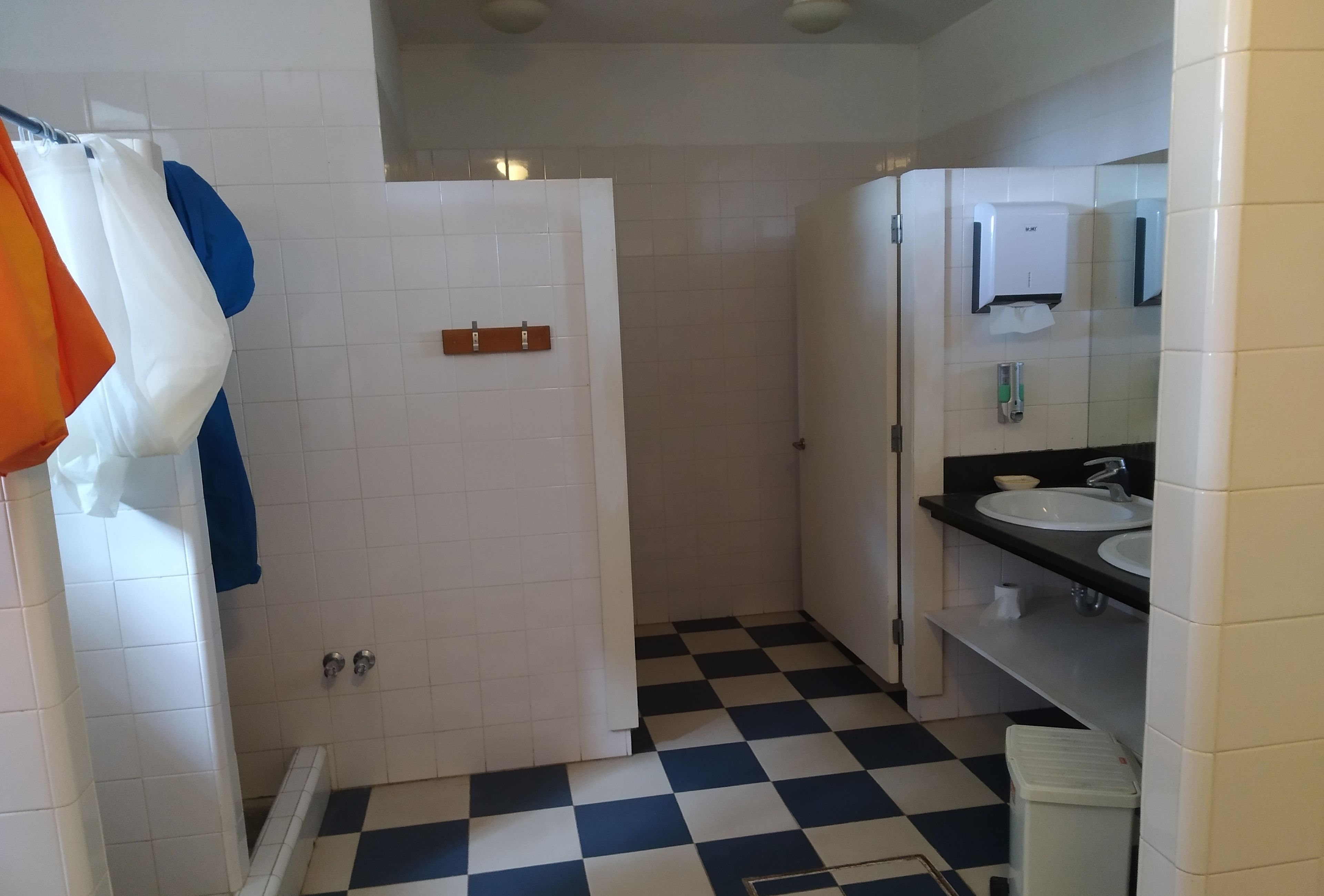 Une salle de bain avec un carrelage à motifs, des carreaux blancs, un lavabo et un miroir.