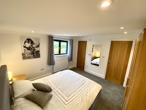 Relax in this inviting bedroom with a large bed, wardrobe, and mirror.