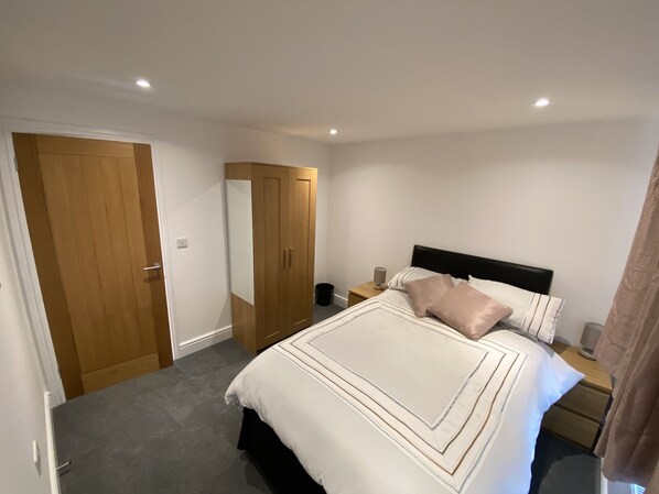 Relax in a serene bedroom with a large bed, wardrobe, and bedside table.