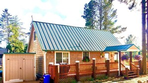 A small, single-story building with a sloped metal roof, a wooden deck, and a covered porch. - The Shell Shack-Darling and peaceful cottage (Pacific City)
