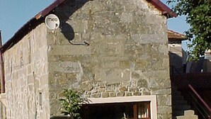 Ein Gebäude aus Stein mit einem geneigten Dach, einer Satellitenschüssel und einem Fenster.