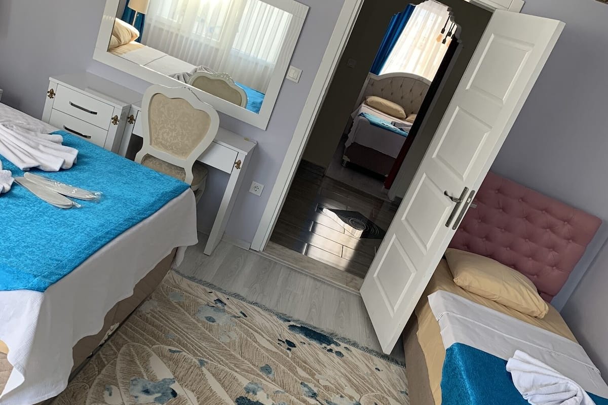 A hotel room with two beds, a desk, a mirror, and a bathroom visible through an open door.