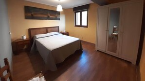 A bedroom with a bed, a nightstand, a wardrobe, a window, and a painting on the wall. - House in Galizano with garden (Cantabria)
