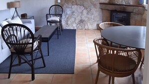 A cozy living area with a stone wall, a fireplace, a dining table with chairs, and a sofa. - House in Galizano with garden (Cantabria)
