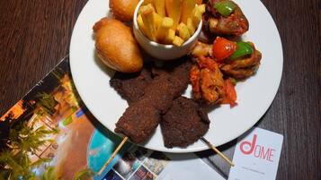 A plate of food with fries, chicken, and bread on a wooden table.