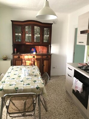 Een koelkast, een oven, een kookplaat, kookgerei, borden en bestek