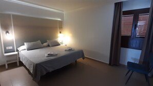 Une chambre à coucher avec un lit, des lampes de chevet, une chaise et une fenêtre avec des stores.