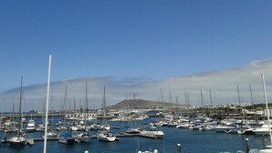 Un port de plaisance où sont amarrés de nombreux bateaux, un ciel dégagé et une montagne qui se profile à l’horizon.