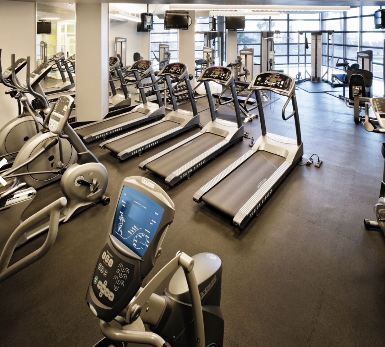 Une salle de sport équipée de plusieurs tapis de course, de vélos d’appartement et d’un appareil d’aviron.