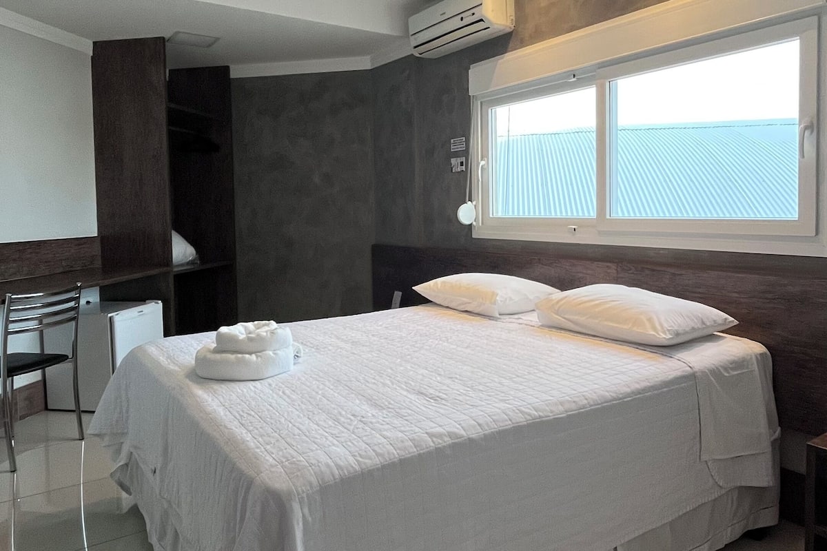 Ein modernes Hotelzimmer mit einem großen Bett, einem Schreibtisch und einem Fenster mit Blick.