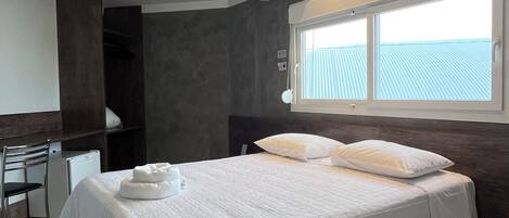 Una habitación de hotel moderna con una cama grande, un escritorio y una ventana con vistas.