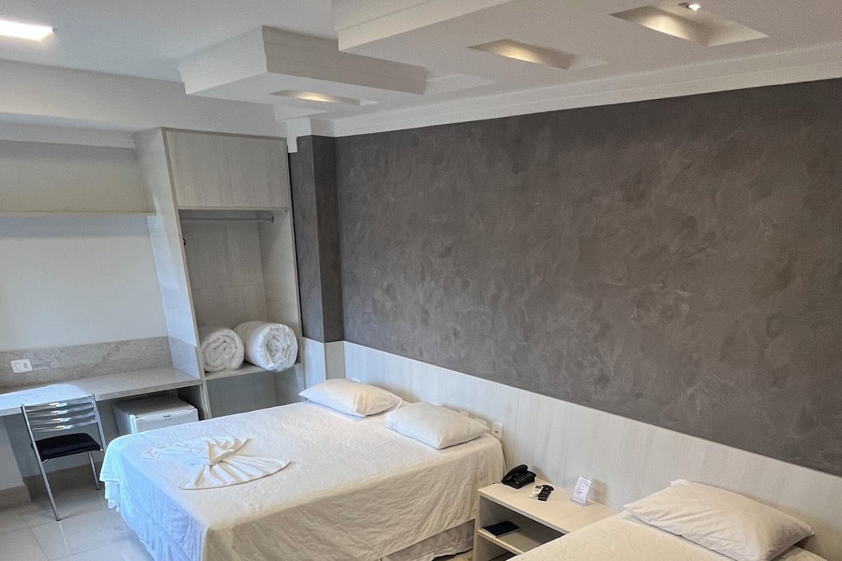 Ein Hotelzimmer mit zwei Betten, einem Schreibtisch und einem Stuhl.
