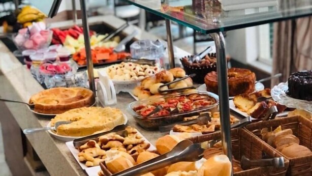 Un buffet proposant une variété de plats et un vase de fleurs rouges placé sur un comptoir en verre.