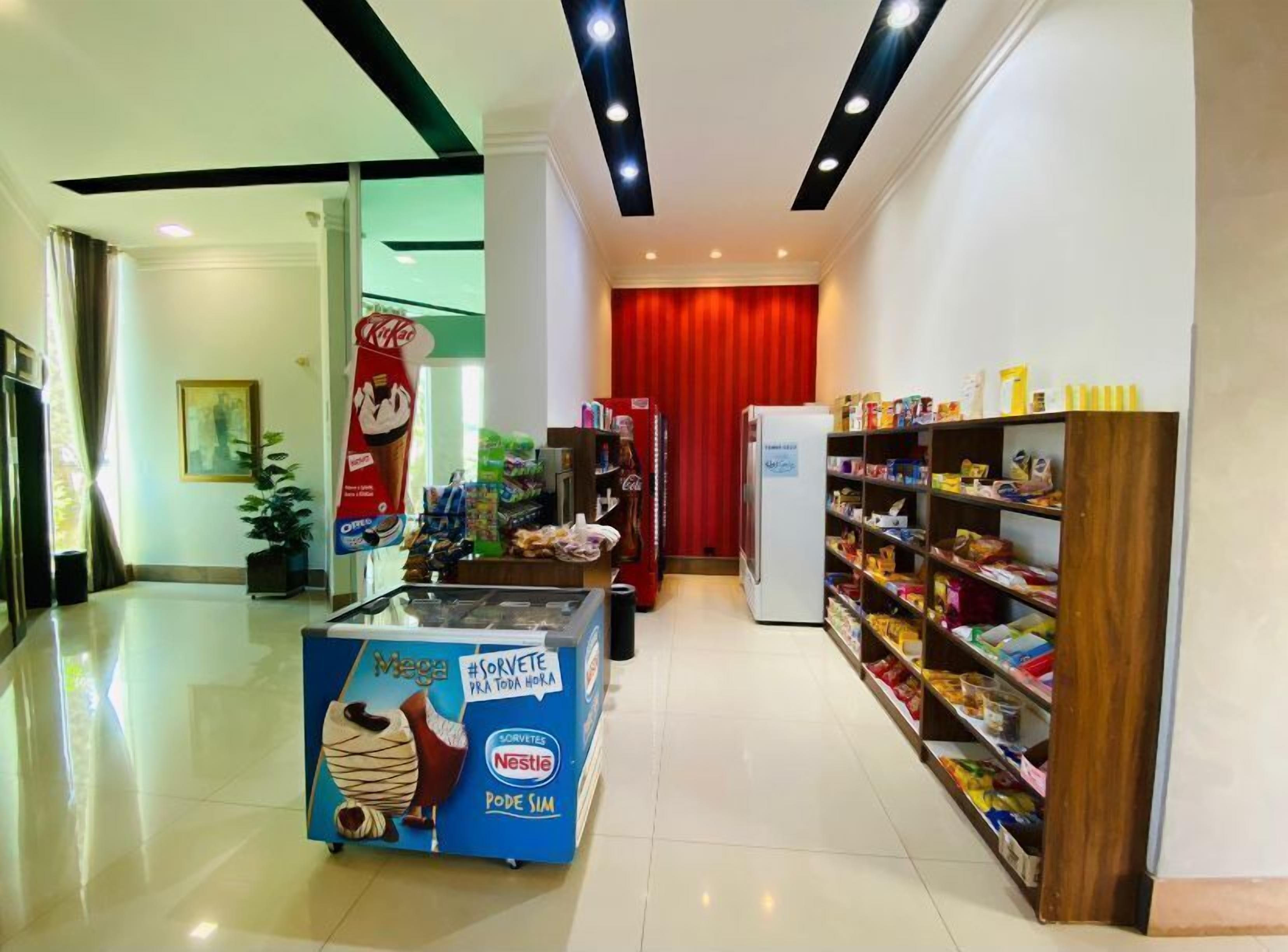 A corridor with a Nestle ice cream display, a red curtain, and shelves stocked with snacks.