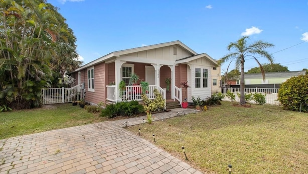 A single-story house with a front porch, a brick pathway leading to the entrance, and a well-maintained lawn. - Gardens, St. Mary's, JFK, Good Samaritan, VA (West Palm Beach)