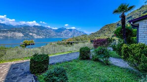 A stone pathway leading to a scenic overlook with a view of a lake and mountains. - Garden Residence Malcesine Lake View  App. G1 (Malcesine)